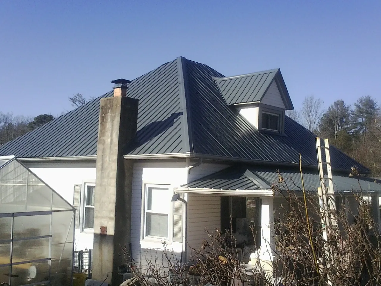Dark blue standing seam metal roof on a white farmhouse with dormer — Slate & Tile Roof Repair by Roofing Brothers in Greeleyville