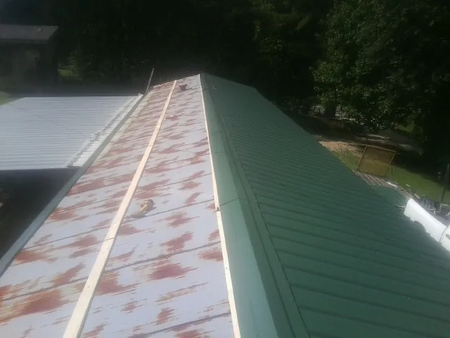 Old rusted panels beside newly installed green metal roofing — Wind Damage Roof Repair by Roofing Brothers in Greeleyville