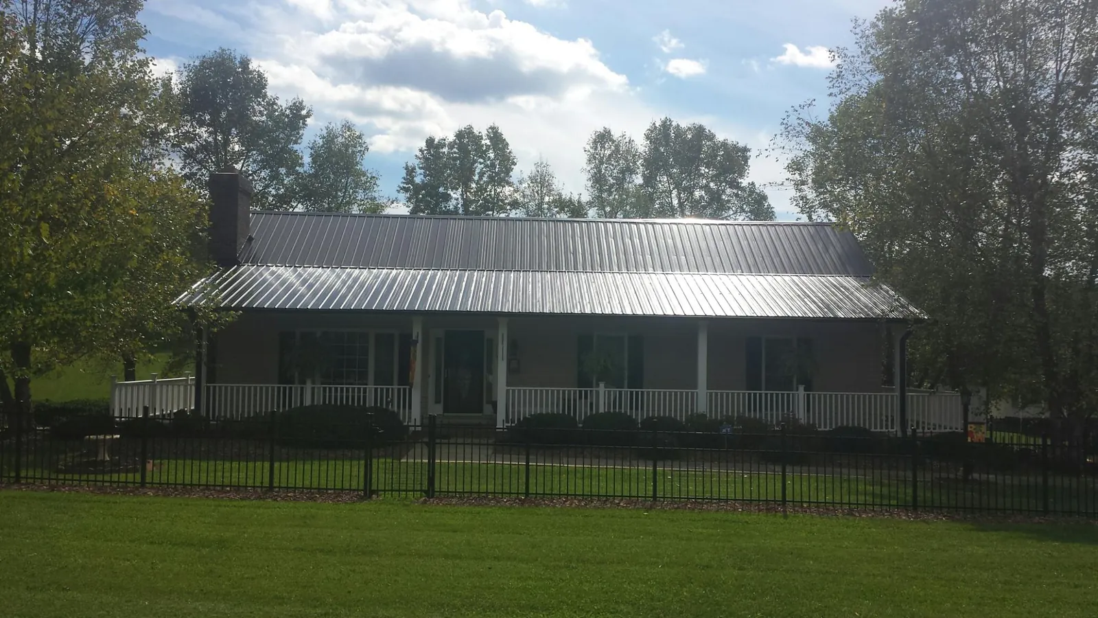 Gray metal roof on a brick ranch with a full width front porch — Gutter Guard Installation work by our crew in Greeleyville
