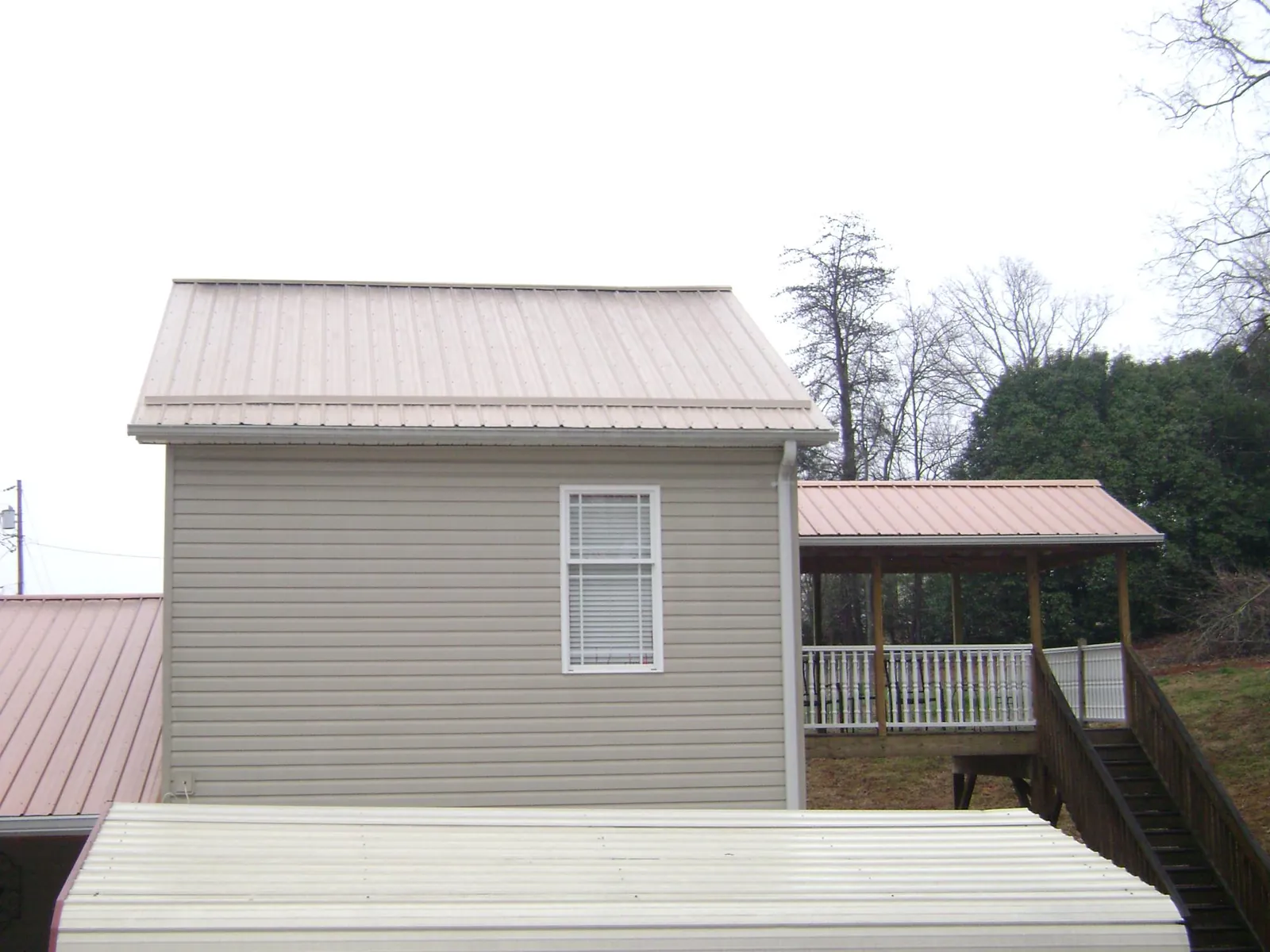 Tan metal roofs on a two story addition and attached porch, from a Roof Replacement job in Greeleyville