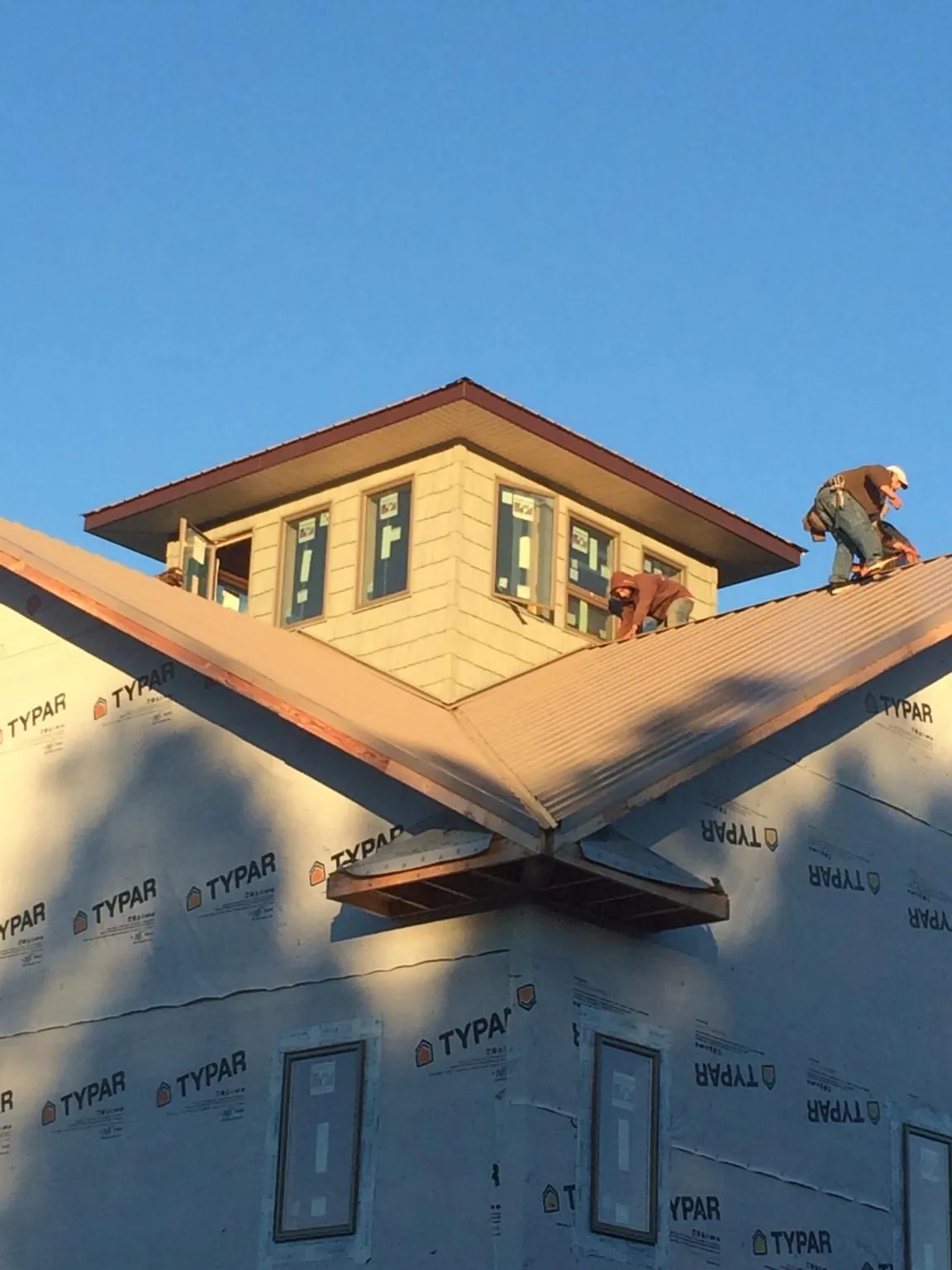 Roofers working around a rooftop cupola on a new metal roof at sunset — Roof Waterproofing in Greeleyville by Roofing Brothers
